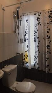 a bathroom with a toilet and a shower curtain at Arka's Elegant Condos in Zamboanga