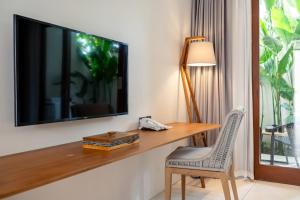 a room with a desk and a television on a wall at IZE Canggu by LifestyleRetreats in Canggu