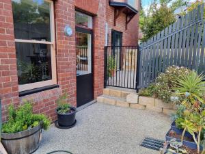 une maison en briques avec une porte noire et quelques plantes dans l'établissement Lords Rest Apartment - Private and Central with Free Parking and Great WIFI, à Hobart