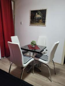 a dining room table with white chairs and a plant on it at Vila Mala Evropa in Leskovac