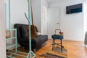 a living room with a black leather chair and a table at Casa El Palo in Málaga