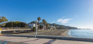 una playa con un puente, agua y palmeras en Casa El Palo, en Málaga