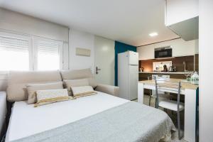 a bedroom with a white bed and a kitchen at Casa El Palo in Málaga