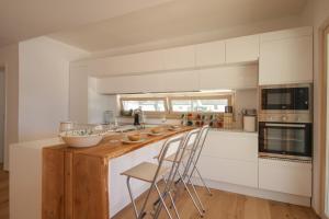 uma cozinha com armários brancos e uma ilha de madeira com bancos em Trulli Dimore - Villa Fico Jo em Polignano a Mare