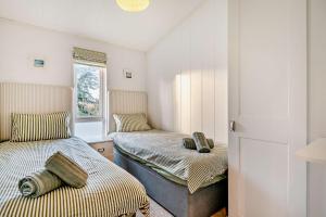 a small room with two beds and a refrigerator at Belvedere Lodge, Shorefield Country Park, Shorefield Rd, Milford on Sea, Lymington SO41 0LH in Lymington