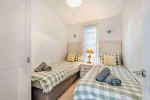 two twin beds in a small bedroom with a window at Belvedere Lodge, Shorefield Country Park, Shorefield Rd, Milford on Sea, Lymington SO41 0LH in Lymington