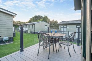 a patio with a table and chairs on a deck at Belvedere Lodge, Shorefield Country Park, Shorefield Rd, Milford on Sea, Lymington SO41 0LH in Lymington