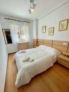 a large white bed in a white bedroom with wooden floors at Apartment Costa Azahar II Ref 012 in El Borseral +23 photos