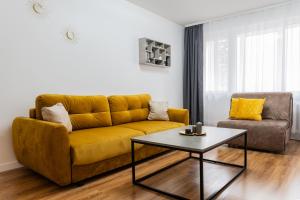 een woonkamer met een gele bank en een salontafel bij A.P. Yellow Apartment in Šiauliai