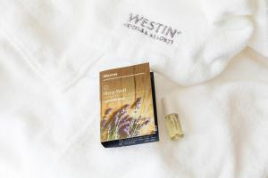 a book and a candle on a white blanket at The Westin Desaru Coast Resort in Desaru