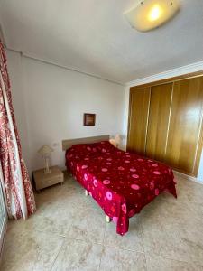 a bedroom with a bed with a red bedspread with hearts at Apartamento Vacacional Vela Blanca Moncofa Ref 055 in Peniscola