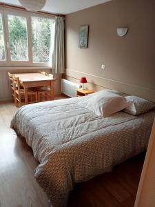 Résidence LE BEC DE L'AIGLE في لو ليوران: غرفة نوم بسرير وطاولة ونوافذ