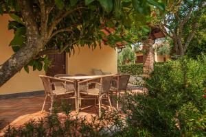 eine Terrasse mit einem Tisch und Stühlen unter einem Baum in der Unterkunft Resort Capalbio in Capalbio