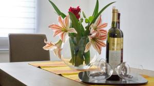 a bottle of wine and a vase of flowers on a table at Apartments Pravica in Trebinje