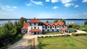 a large white building with an orange roof at Hotel Joseph Conrad in Pisz