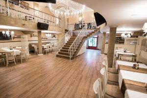 a restaurant with a staircase and tables and chairs at Hotel Victoria in Panagyurishte