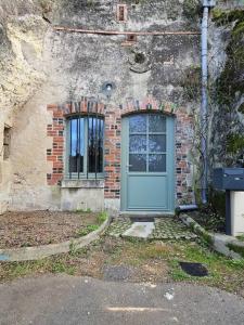 un edificio de ladrillo con una puerta azul y una ventana en Charmante maison troglodyte Loire Valley en Rochecorbon