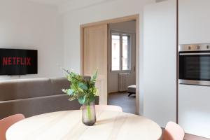 una sala de estar con una mesa blanca con un jarrón de flores en New Exclusive Melegnano Apartments- Near train station en Melegnano