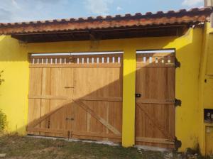 una casa gialla con due porte in legno per il garage di Morada de Angatu a Itanhaém Altre 5 foto