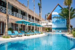 a pool at the resort with blue chairs and umbrellas at IZE Canggu by LifestyleRetreats in Canggu