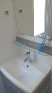 a bathroom sink with a mirror and a toothbrush at Happy Camp mobile homes in Camping La Vecchia Torre in Gallipoli
