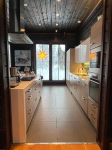 a kitchen with white cabinets and a large window at Grand Hideout Levi in Kittilä