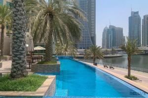 een zwembad met palmbomen en een stad bij Gorgeous 1BR at Park Island Blakely Dubai Marina by Deluxe Holiday Homes in Dubai