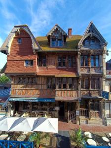 a large wooden building with tables in front of it at Hotel La R&eacute;sidence Manoir De La Salamandre in &Eacute;tretat