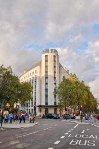 duży budynek na ulicy miejskiej z ludźmi chodzącymi wokół niego w obiekcie ME London by Melia - Covent Garden w Londynie
