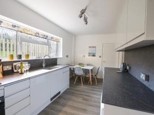 a kitchen with white cabinets and a table with chairs at Hook Farm Cottage in Lyme Regis