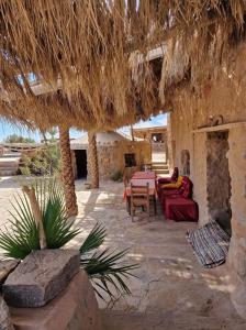 un patio avec des canapés et des tables ainsi qu'un toit de paille dans l'établissement Maison Boutchrafine, à Erfoud