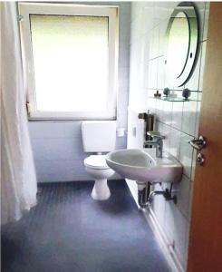uma casa de banho com um WC, um lavatório e uma janela em 4 Zimmer Wohnung zentral in Osnabrück em Osnabrück