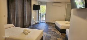 Una habitación de hotel con dos camas y un televisor. en HOSTAL NERVION, en Sevilla