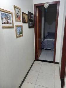 - un couloir avec une chambre dotée d'un lit et de photos sur le mur dans l'établissement Apartamento Todos os Santos próximo da Unimontes, à Montes Claros