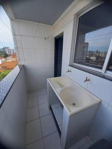 La salle de bains blanche est pourvue d'un lavabo et d'une fenêtre. dans l'établissement Apartamento Todos os Santos próximo da Unimontes, à Montes Claros