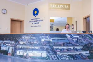 a woman standing behind a display case in a building at Hotel Uniwersytecki in Toruń