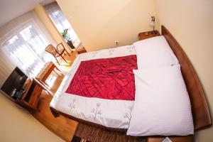 a bedroom with a bed with a red and white comforter at Hotel Uniwersytecki in Toruń