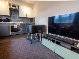 uma cozinha com uma grande televisão e bancos de bar pretos em Newly renovated ideally situated 2 bedroom flat em Bournemouth