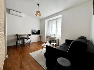 un salon avec un canapé noir et une table dans l'établissement Appartements Climatisés Centre-ville / 10 personnes, à Besançon