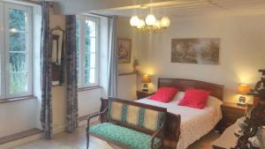 Un dormitorio con una cama con almohadas rojas y una silla en A la Grenouille du Jura, en Bellignat