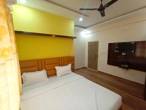 a bedroom with a bed and a tv on the wall at STAYMAKER Karanji Paradise - Next to Liquor station in Bangalore