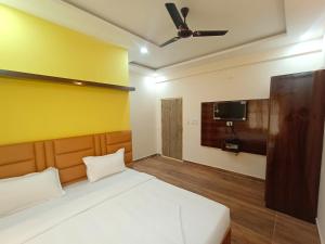 a bedroom with a bed with a yellow wall at STAYMAKER Karanji Paradise - Next to Liquor station in Bangalore