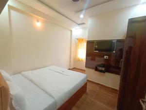 a bedroom with a white bed and a television at STAYMAKER Karanji Paradise - Next to Liquor station in Bangalore