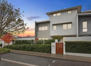 una casa con un estacionamiento delante de ella en Stylish & Modern Townhouse in Canberra en Harrison