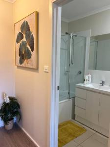 y baño con ducha, lavabo y espejo. en Stylish & Modern Townhouse in Canberra en Harrison