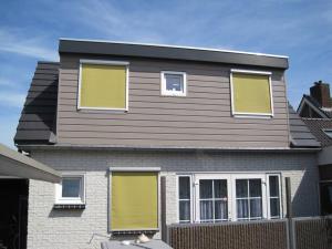 ein Haus mit gelben Fensterläden darauf in der Unterkunft Modern zomerhuis voor 4 personen in Wijk aan Zee
