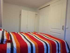 uma cama com um cobertor listrado colorido em Modern zomerhuis voor 4 personen em Wijk aan Zee