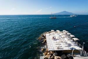 a dock with chairs and a boat in the water at Grand Hotel Cocumella in Sant'Agnello