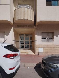 une voiture blanche garée devant un bâtiment dans l'établissement Au Bord du palmier, à Rabat