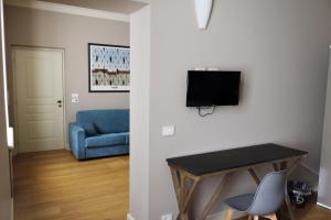 a living room with a blue couch and a television on a wall at Albergo '900 in Quattordio